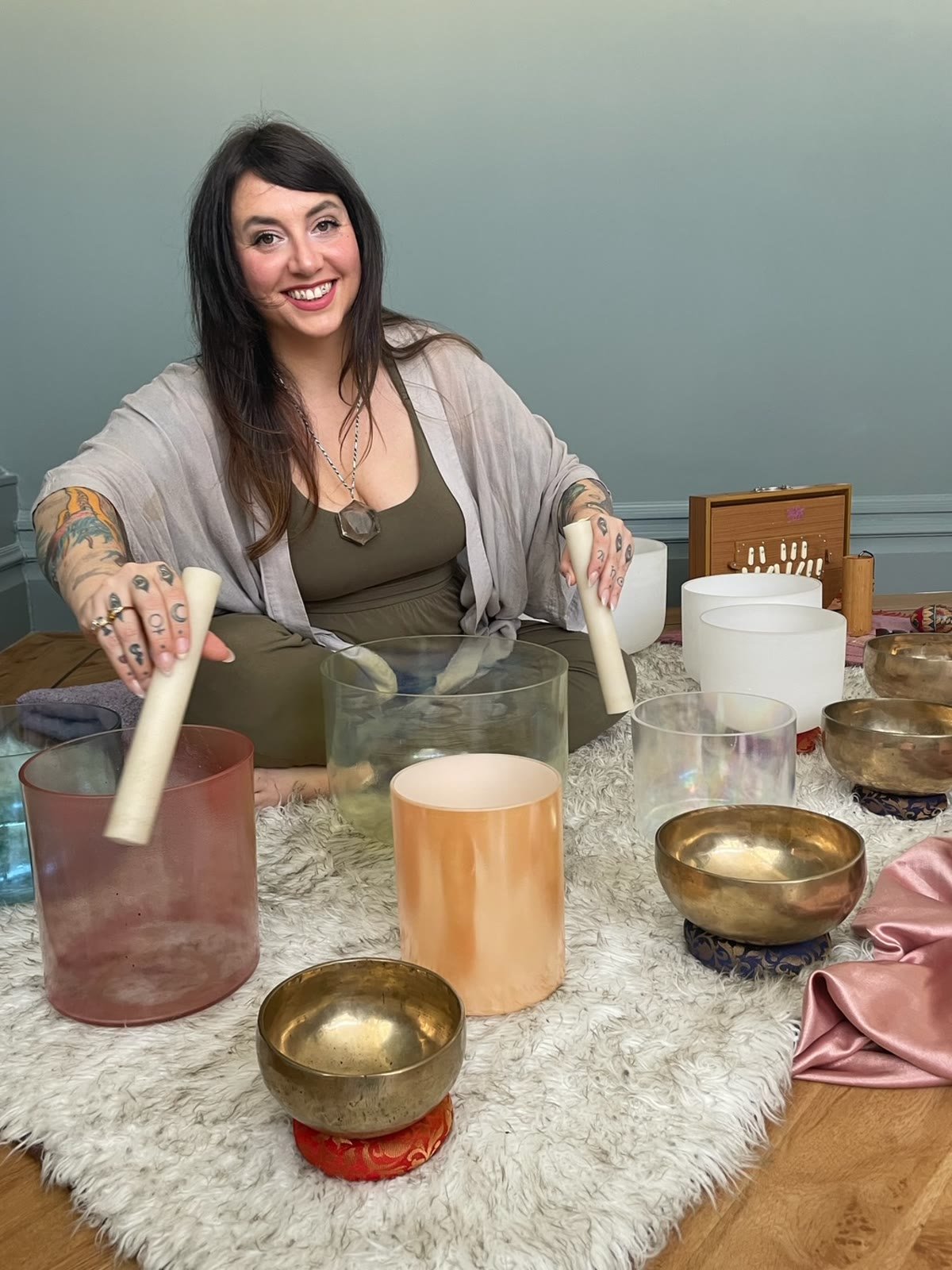 Nicola Buffa seated with her quartz crystal and alchemy singing bowls, set out on a sheepskin for a Soundbath